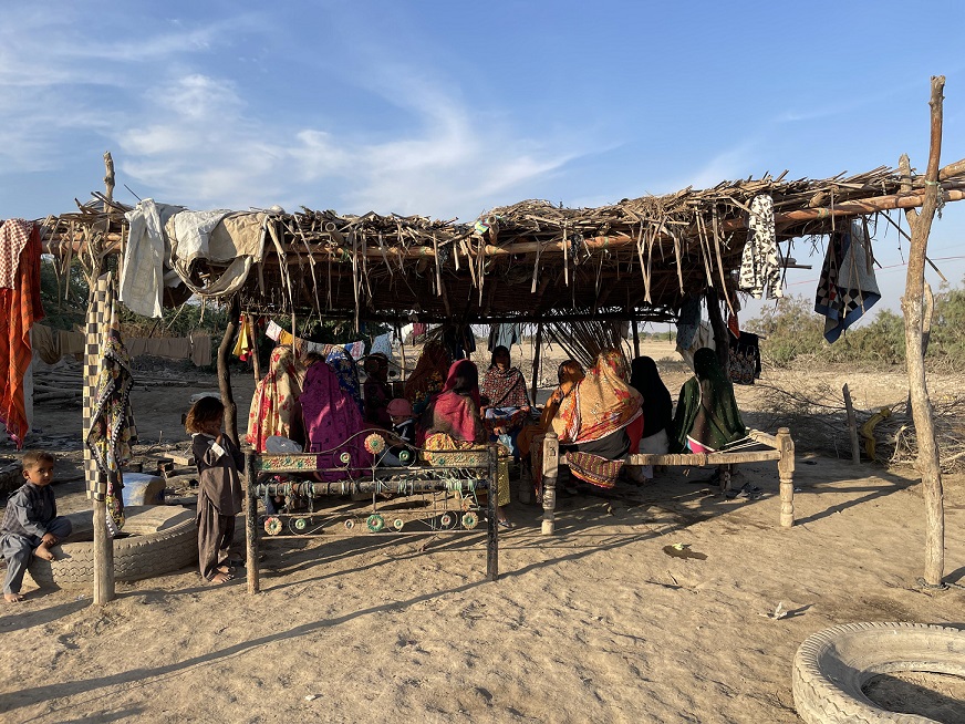 A few pregnant women sitting under an open hut at Chowki Jamali, a roof they sleep underneath often.