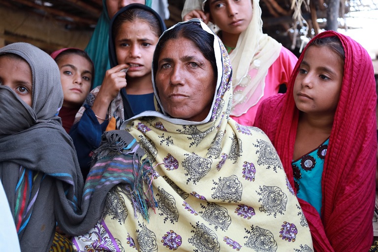  Mai Jori sitting on a charpoy, surrounded by villagers