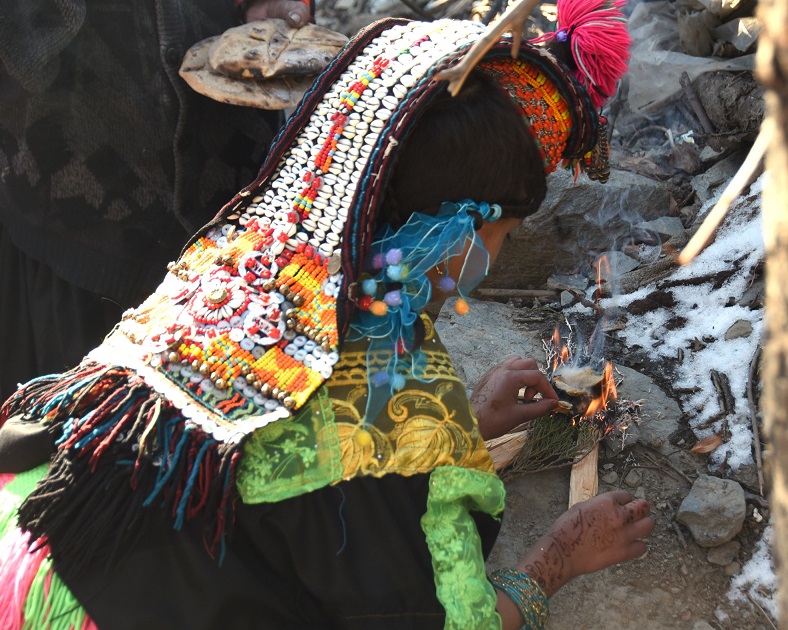 A young Kalasha is trying to light a fire&nbsp;to heat food