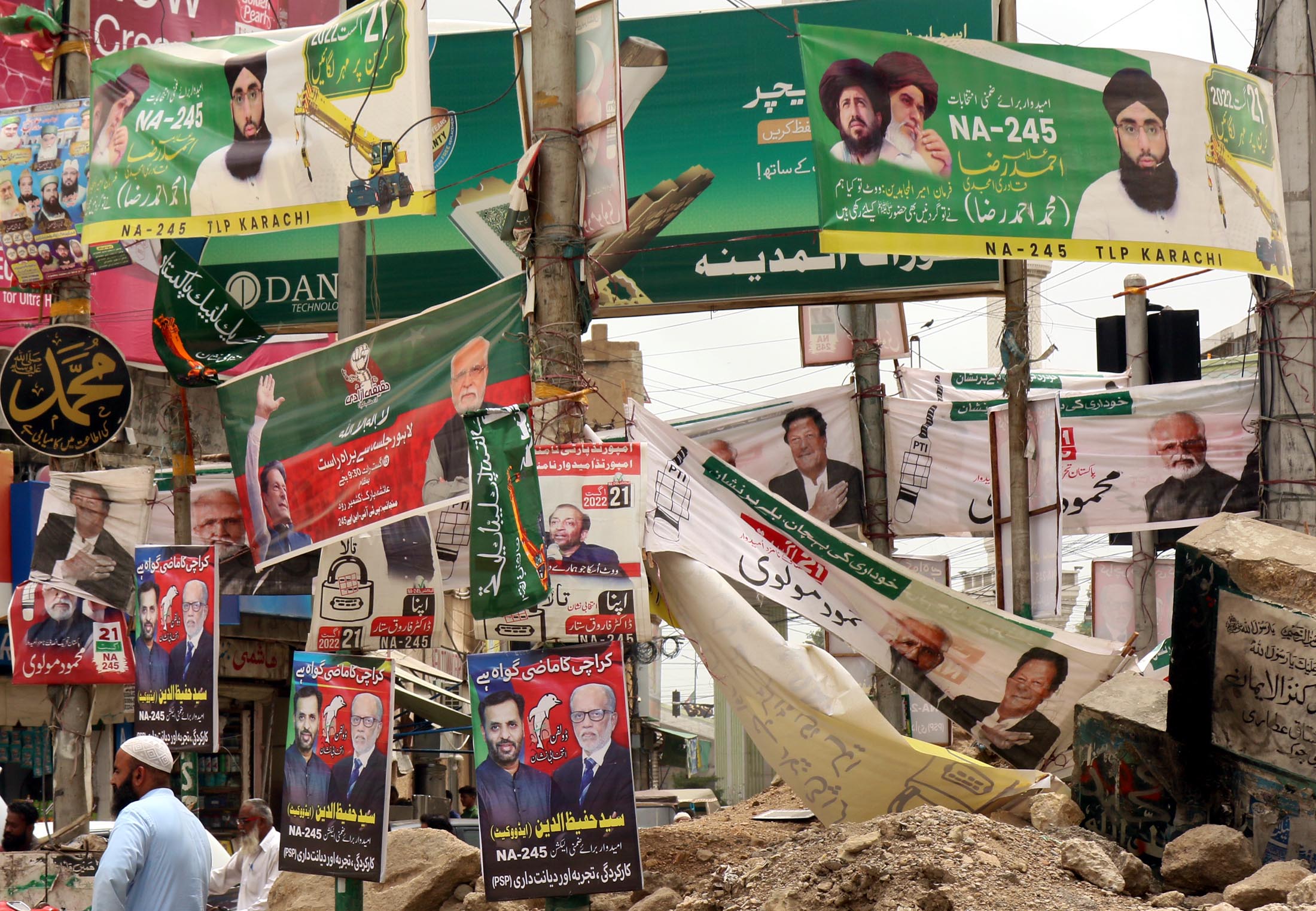 Election banners above a dug-up sewerage line in NA-245