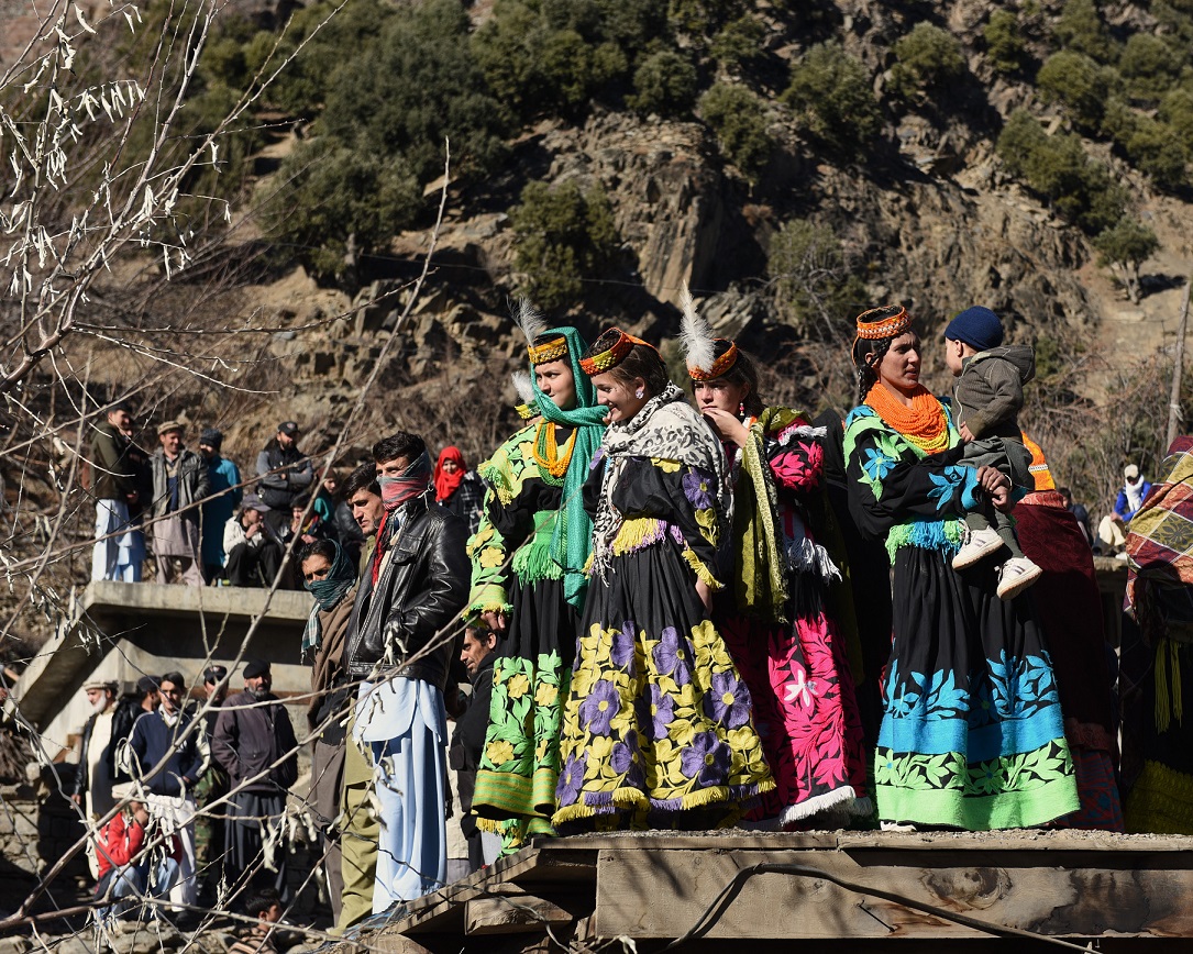 Some Kalasha women are standing on a rooftop (Photo by Srosh Anwar)